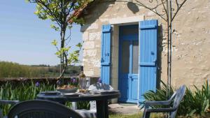 stół i krzesła przed niebieskimi drzwiami w obiekcie Le Guet de Chouette w mieście Obterre