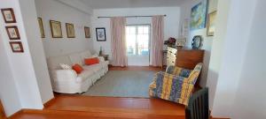 a living room with a white couch and a chair at Vivenda Faria in Vila Nova de Milfontes