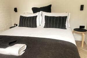 a large white bed with black and white pillows at The Cabin at Barnstormers, luxury woodland setting in Marldon