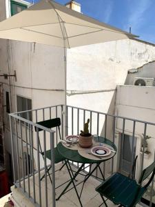 a table and chairs on a balcony with an umbrella at Casetta del vicolo orologio in Cisternino