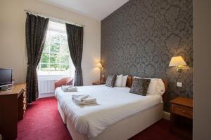 a hotel room with a large bed and a window at Wortley Hall Sheffield in Barnsley