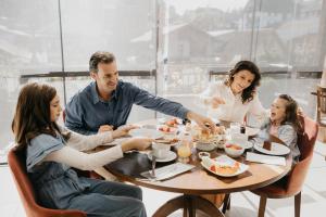 Eine Familie sitzt um einen Tisch und isst. in der Unterkunft Hotel Fioreze Centro in Gramado