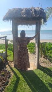 Una mujer está de pie en una cabaña en la playa en Club Manguaba Beira Mar, en Japaratinga