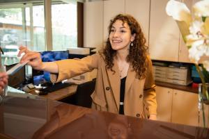 a woman standing at a counter in an office at Hotel Lumin in Cremia