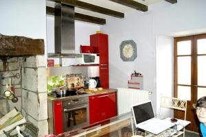 a kitchen with red cabinets and a laptop on a table at Maison de 5 chambres avec vue sur le lac jardin clos et wifi a Menet in Menet