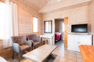 een woonkamer met een televisie en een tafel en stoelen bij Lapland Hotels Ounasvaara Chalets in Rovaniemi