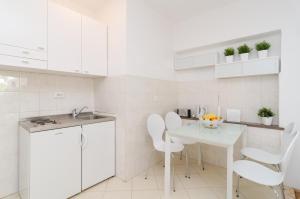 una cocina con armarios blancos y una mesa y sillas blancas. en House Apartments Ariva, en Dubrovnik