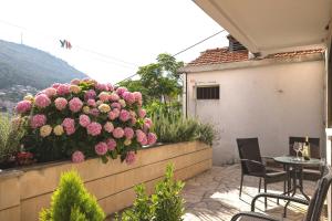 un patio con flores rosas en la pared en House Apartments Ariva, en Dubrovnik