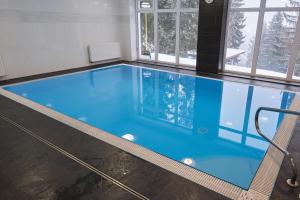 ein großer Swimmingpool mit blauem Wasser in einem Zimmer in der Unterkunft Wellness Penzion Kotár in Prostřední Bečva