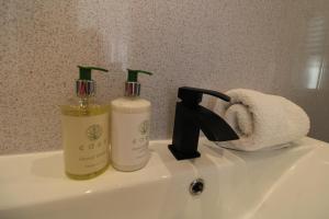 a bathroom sink with two bottles of soap and a towel at Clifton Villa Guest House in Llandudno