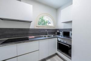 uma cozinha com armários brancos, um lavatório e uma janela em Il Golfo Apartments Duplex em Toscolano Maderno