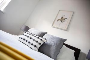 1 cama con almohadas y una foto en la pared en Superb Apartment in Stratford upon Avon with Free Parking & Wi-Fi, en Stratford-upon-Avon
