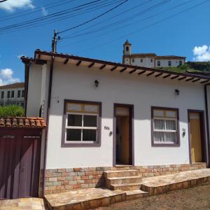 a small white house with a brick wall at Trenzin de Aconchego Apto no Centro Histórico in Ouro Preto
