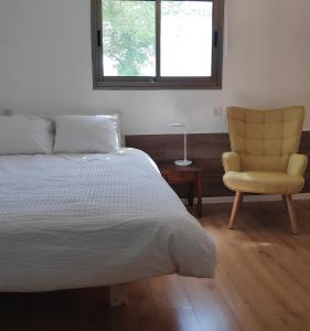 een slaapkamer met een bed en een gele stoel bij אחת ויחידה - One & Only in Ma'alot-Tarshiha