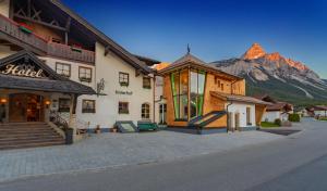 a building on a street with a mountain in the background at Hotel Tirolerhof - Familotel Zugspitze in Ehrwald