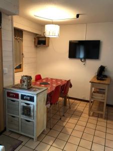 a kitchen with a table and a television on the wall at Studio 4 personnes RDC avec jardin et parking sous terrain in Samoëns