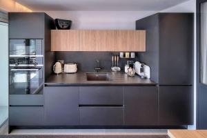 a kitchen with black cabinets and a sink at Cannes Luxury Rental - Stunning sea front apartment in Villeneuve-Loubet