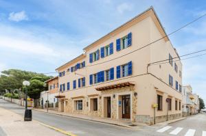 budynek z niebieskimi oknami na ulicy w obiekcie Hostal Marina w Cala Ratjada