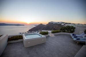 Sunset View Villa Santorini - with Outdoor Jacuzzi في فِروستيفاني: حوض استحمام ساخن على فناء مطل على المحيط