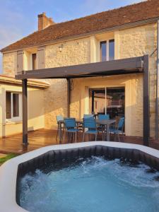 un patio con bañera de hidromasaje frente a una casa en L'inattendu, jolie maison briarde avec jacuzzi en Chenoise