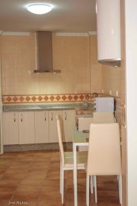 uma cozinha com armários brancos e uma mesa e cadeiras em 2 bedrooms appartement with wifi at Penaflor em Peñaflor