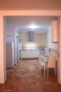 uma cozinha com mesa e electrodomésticos brancos em 2 bedrooms appartement with wifi at Penaflor em Peñaflor