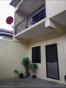 a building with a balcony and two potted plants at Kylitas transient house- Bohol in Tagbilaran City