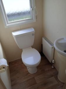 een badkamer met een toilet, een wastafel en een raam bij 6 berth Seawick Caravan Park, St Osyth in Colchester