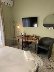 Habitación de hotel con escritorio, silla y TV. en DIMORE MORELLI en Amantea