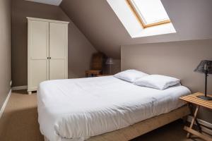 Schlafzimmer mit einem großen weißen Bett und einem Dachfenster in der Unterkunft Gîte Le Bisquin in Cancale