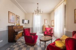 a living room with red chairs and a piano at il buen retiro in Lucca