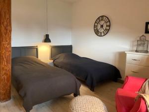 a bedroom with two beds and a clock on the wall at Gut Alt Farpen Ferienwohnung 4 in Blowatz