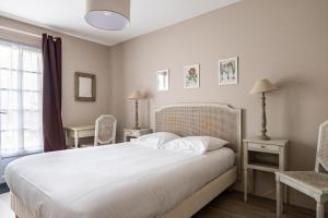 une chambre avec un grand lit blanc et deux chaises dans l'établissement Gîte Taumain, à Cancale