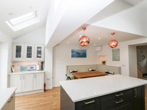 a kitchen and dining room with white cabinets and a table at Gerallt in Pwllheli