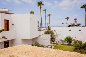 ein weißes Haus mit Palmen im Hintergrund in der Unterkunft Bungalow Costa Adeje Cortijo 1-8 in Playa de las Americas