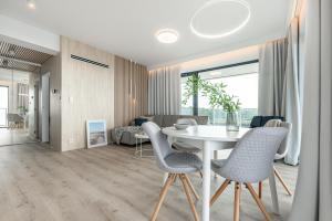 a dining room and living room with a white table and chairs at Apartament Morskie Widoki in Darłówko