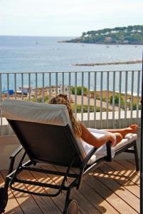 a woman laying in a hammock on a balcony overlooking the ocean at Royal Antibes - Luxury Hotel, Résidence, Beach & Spa in Antibes