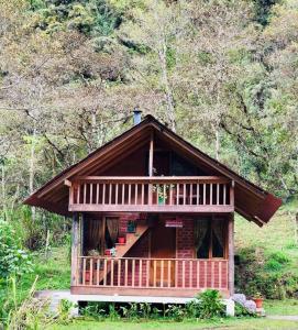 a large wooden cabin with a balcony in a forest at Hospedaje Puntzán in Baños