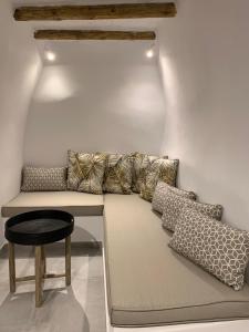 a couch with pillows and a stool in a room at Serenity Living Platia, Tinos in Platiá
