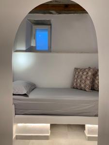 a bed in a white room with a window at Serenity Living Platia, Tinos in Platiá