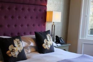 a bedroom with a bed with a purple headboard and a phone at 24 Royal Terrace in Edinburgh