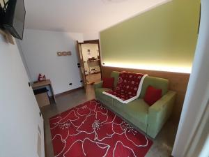 a living room with a green couch and a red rug at Kalipè Dolomiti in Soffranco