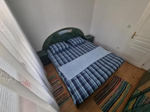 a bed with a blanket on the floor next to a door at Apartman MiG in Berkovac