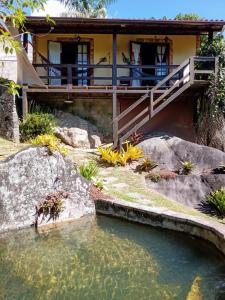 una casa con un estanque delante de ella en OYO Pousada Luar da Serra Lumiar, en Lumiar