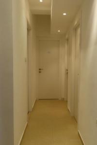 un corridoio vuoto con pareti bianche e una porta di B12 Inn a Gerusalemme