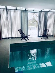 a swimming pool with two chairs in front of a window at Mulina River Lodge in Pribanjci