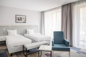 um quarto de hotel com duas camas e uma cadeira azul em Magnus Resort em Szczyrk