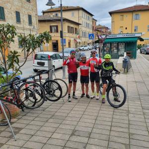 eine Gruppe von Menschen, die neben Fahrrädern auf einem Bürgersteig stehen in der Unterkunft Hotel Ghibellino in Buonconvento