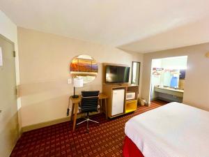 a hotel room with a bed and a desk and a television at Days Inn by Wyndham Athens in Athens