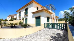een wit huis met een groene poort ervoor bij Porto Santo Casa Dourada in Porto Santo